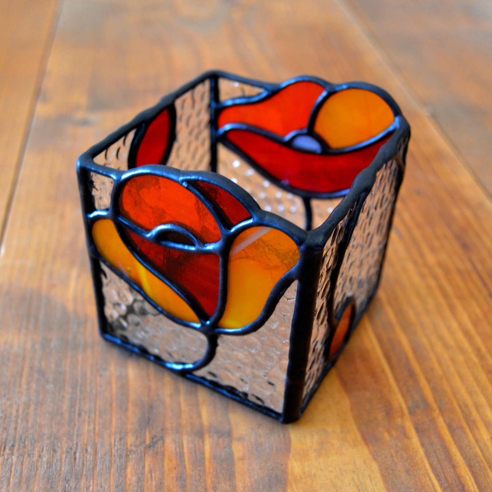 Un bote de vidrio transparente diseñado para sostener una vela, con una estructura resistente y una superficie lisa que permite que la luz de la llama brille con claridad, creando una atmósfera cálida y acogedora en cualquier ambiente.