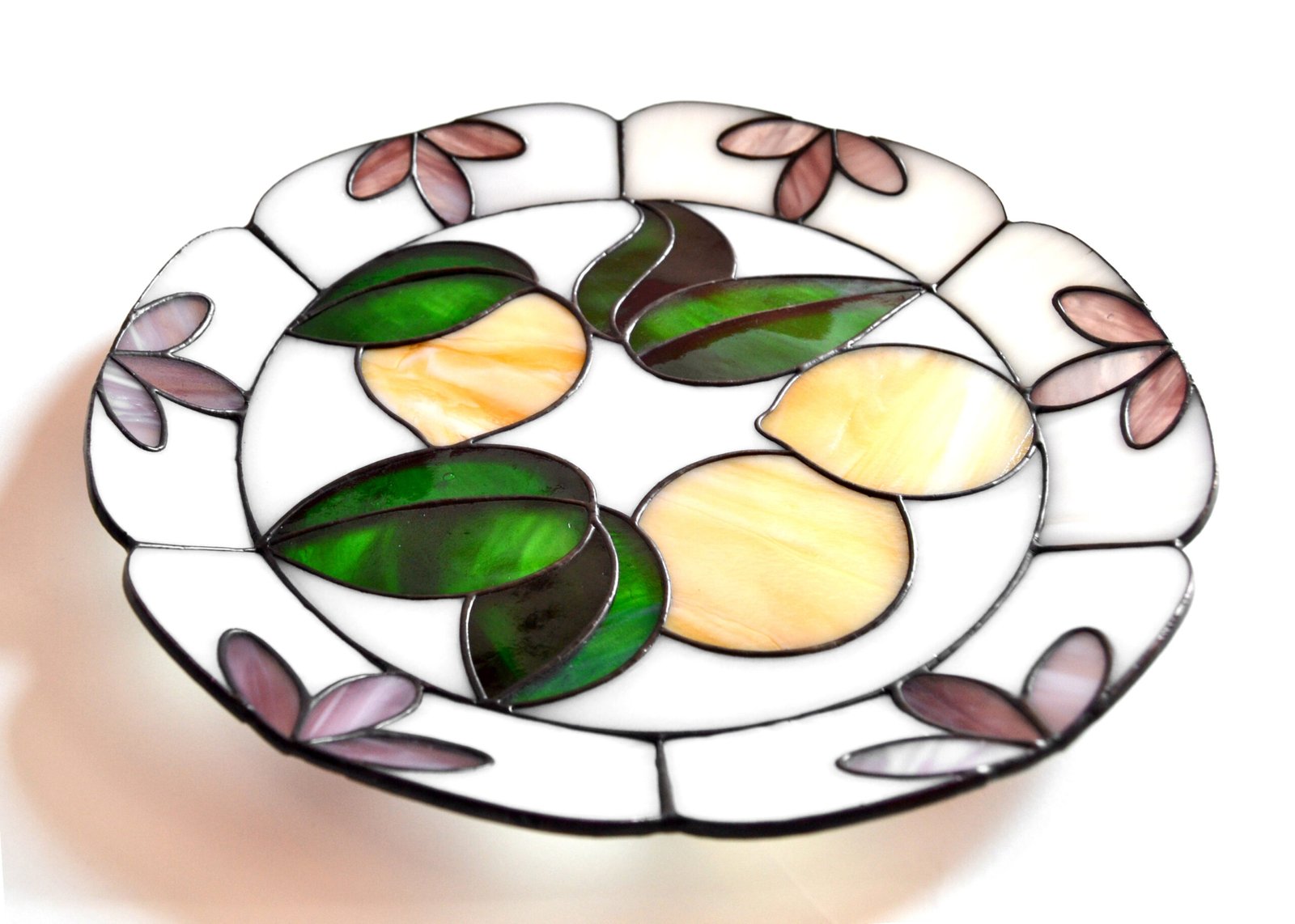 Un plato de vidrio translúcido, con bordes finamente pulidos y una superficie lisa que refleja la luz, creando un efecto sutil pero elegante en cualquier mesa o superficie donde se coloque.