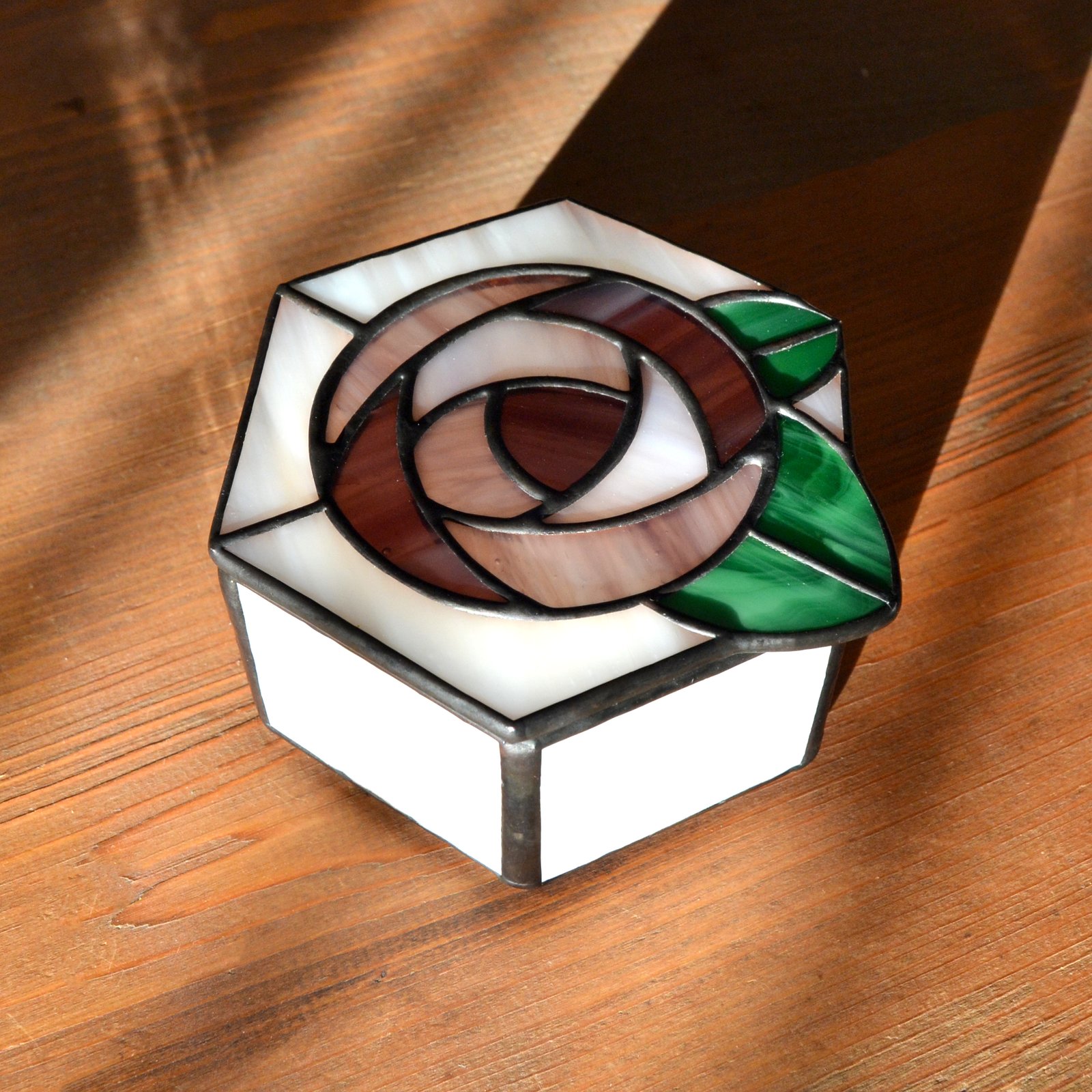 Una caja de vidrio meticulosamente tallada con detalles intrincados que representan una exquisita flor en pleno florecimiento, capturando la belleza y la fragilidad de la naturaleza en una obra de arte transparente.