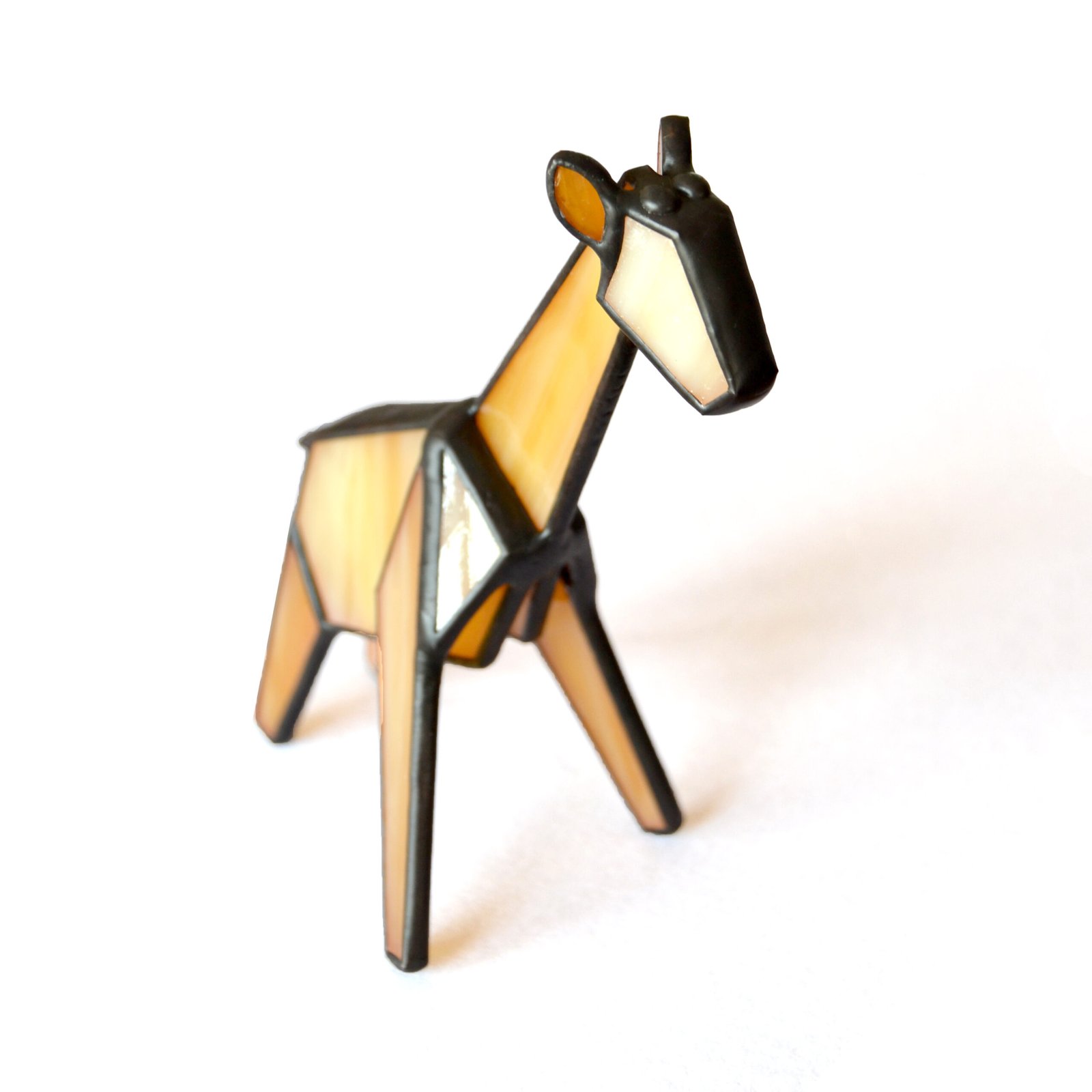 Un vitral en forma de una jirafa, con su cuello largo y elegante, sus manchas distintivas y sus ojos llenos de curiosidad y gracia. La luz del sol ilumina los tonos cálidos y terrosos del vidrio, creando una sensación de serenidad y asombro ante la belleza de la naturaleza.